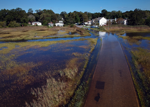 Flooded street with houses seen just beyond the flooding.