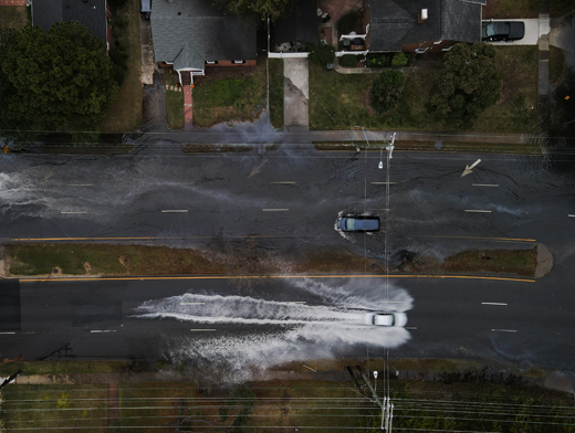 Cars driving in opposite directions down a flooded street.
