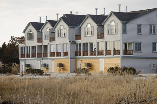 The rear of connected townhomes with elevated utilities installed along the exterior.